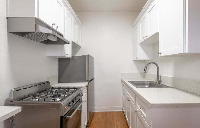 A kitchen with a stove, sink, and cabinets at Westmore Manor Apartments, Los Angeles, CA
