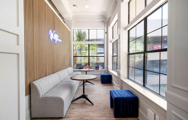 a seating area with a couch and table in a room with large windows