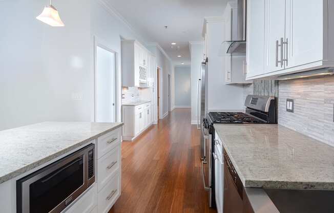 a large kitchen with marble counter tops and white cabinets