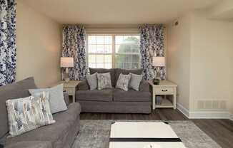 A living room with a grey couch, a coffee table, and a television.