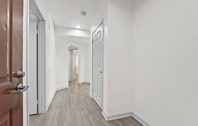 a corridor in a home with white walls and wood floors