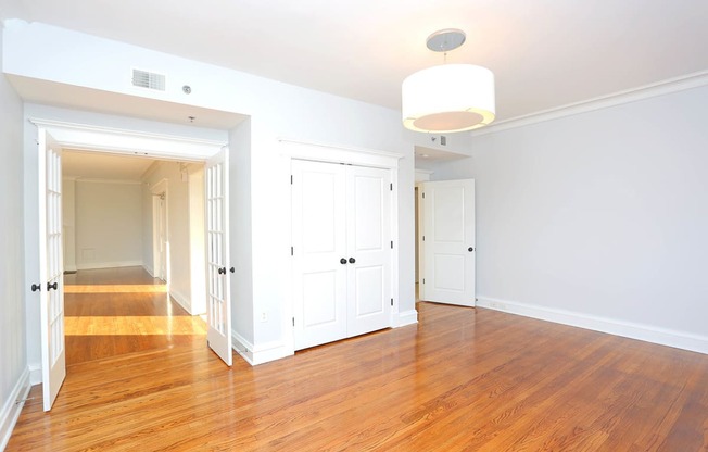 Living room with light wood flooring, white walls, front door and overhead light with shade. at York House, Saint Louis, Missouri