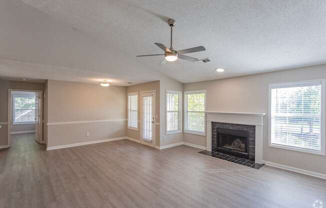 an empty living room with a fireplace and a ceiling fan