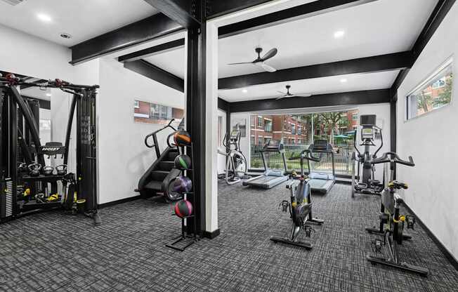 A gym with a variety of exercise equipment including treadmills, stationary bikes, and weight machines.