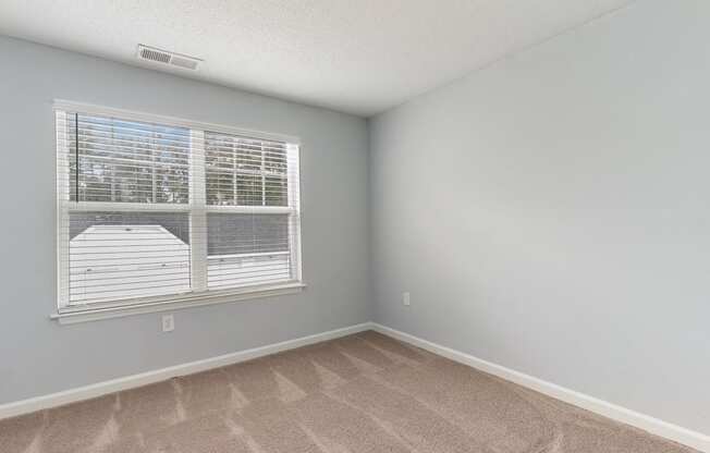 an empty bedroom with a large window and carpeting