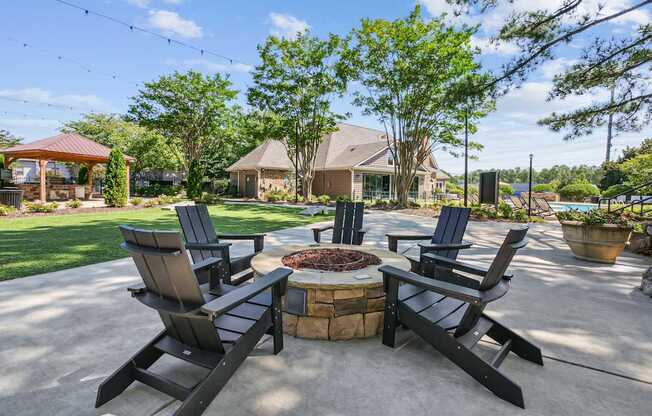 A patio with a fire pit and chairs.