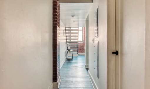 a hallway with a brick wall and a white door