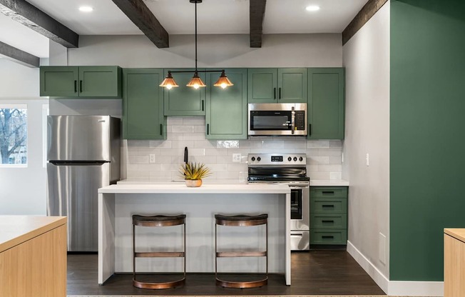 A kitchen with green cabinets and a white island.