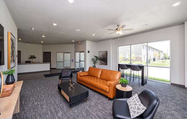 A spacious living room with a brown sofa, a black coffee table, and a ceiling fan.