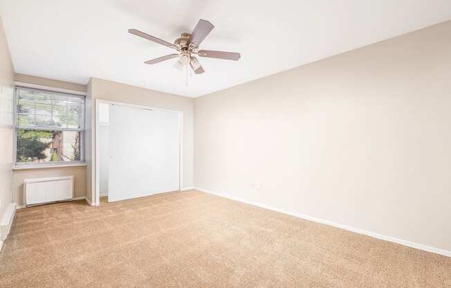 an empty living room with a ceiling fan and a window