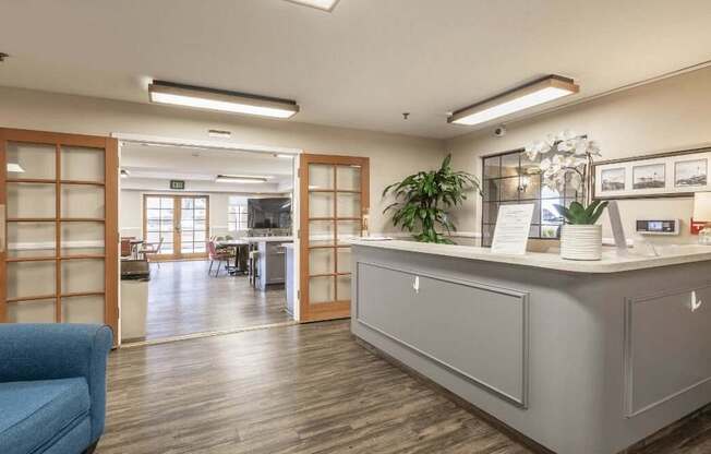 a reception area with a blue couch and a counter in a lobby at Huntington Terrace North Senior, Huntington Beach, CA