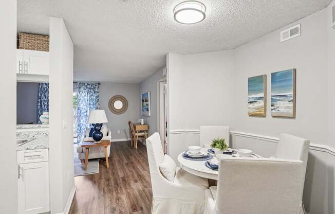A dining room with a table set for two and a painting on the wall.