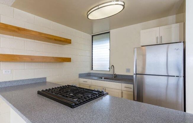 a kitchen with a stove and a stainless steel refrigerator at Palms of Kilani Apartments, Wahiawa, Hawaii