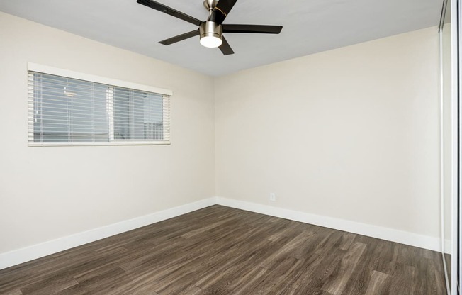 an empty room with a window and a ceiling fan