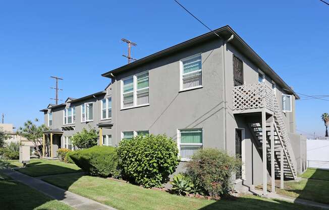 A grey house with a green bush in front.
