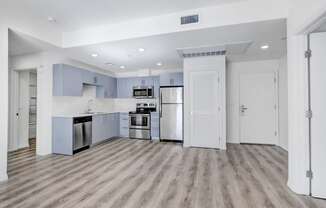 an empty kitchen with stainless steel appliances and blue and white cabinets