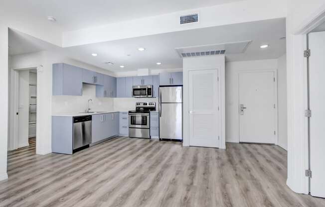 an empty kitchen with stainless steel appliances and blue and white cabinets