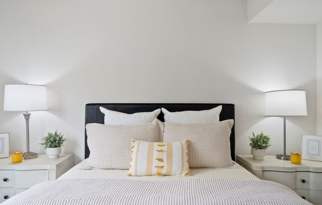 a bedroom with a bed and pillows and two night stands