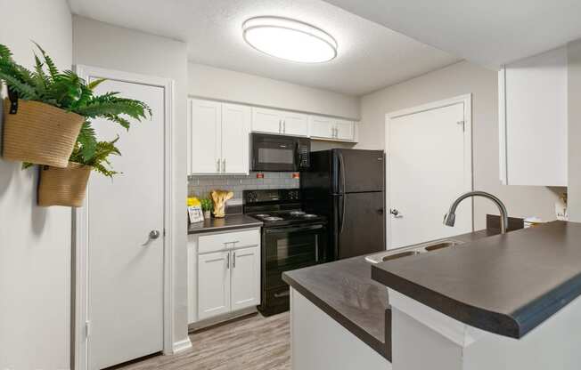 a kitchen with black appliances and white cabinets and a counter top