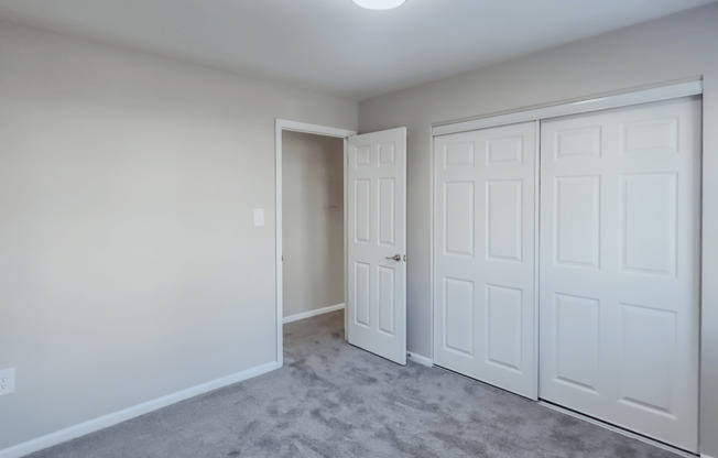 an empty bedroom with two closets and a door to a hallway