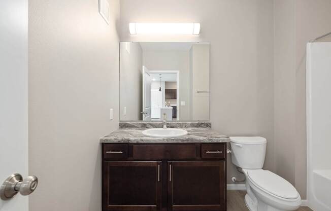 A bathroom with a sink, toilet, and mirror.