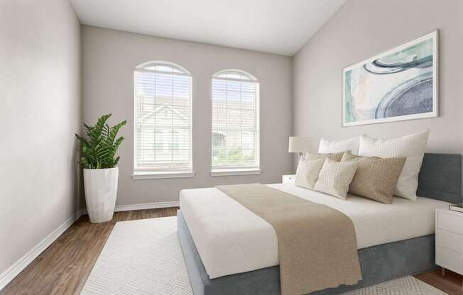 A bedroom with a large bed and a potted plant.