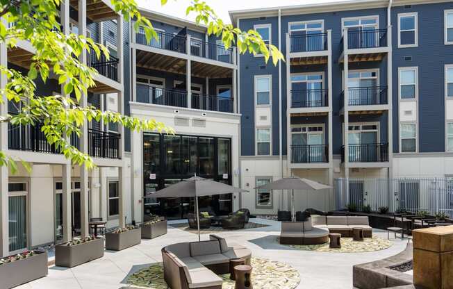 a courtyard with couches and umbrellas in front of an apartment building