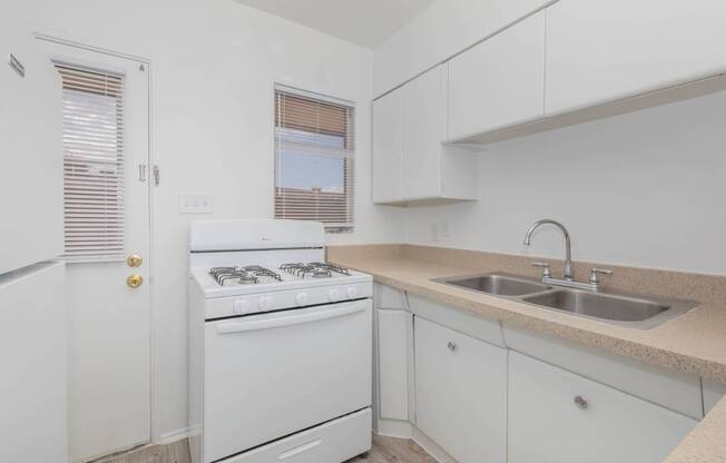 A white kitchen with a sink and a stove.