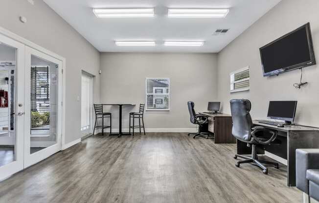 an office with two computers and a tv on the wall