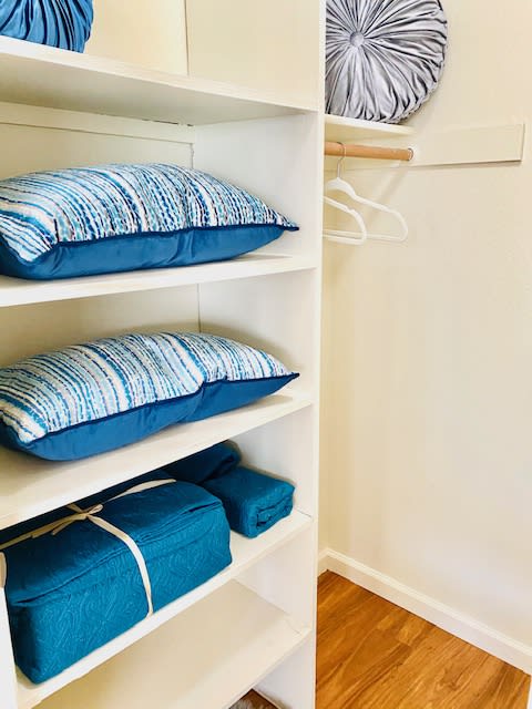 a shelf with pillows on it in a closet