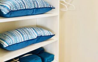 a shelf with pillows on it in a closet