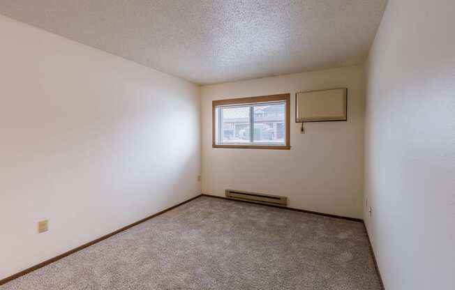 the living room of an apartment with carpet and a window. Fargo, ND Parkwood