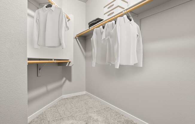 A white shirt is hanging on a wooden hanger in a white closet.