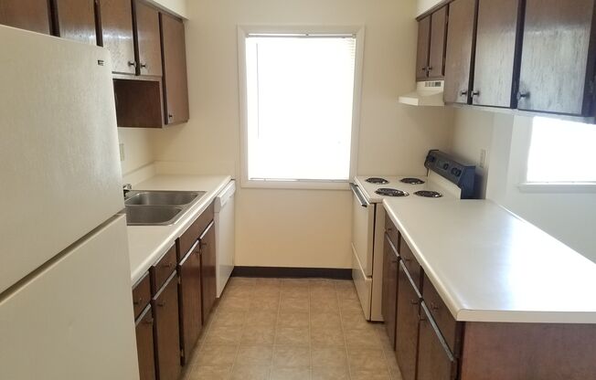 A kitchen with brown cabinets and a white refrigerator.