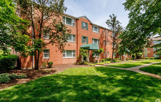 exterior view of a brick apartment building with green grass and trees