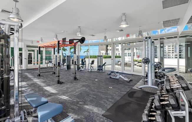 A gym with a variety of equipment including a treadmill, weights, and a bench.