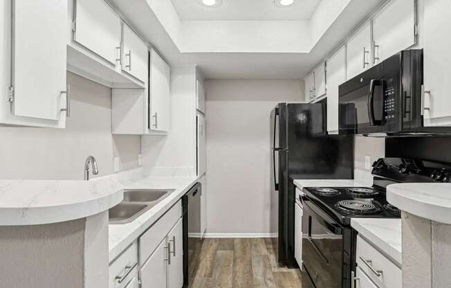 A5 kitchen with black appliances and white cabinets at Windridge on the Parkway apartments in Dallas, TX