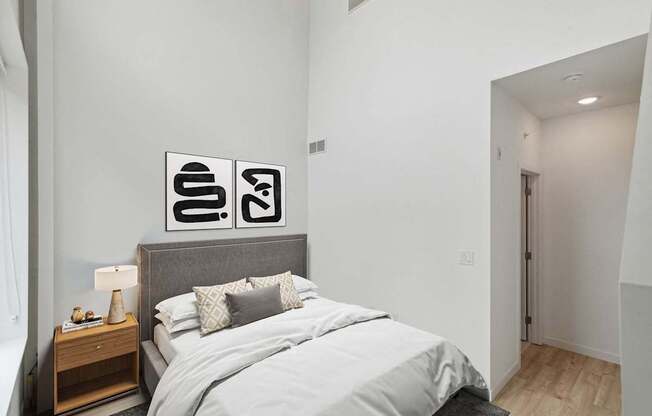 A bedroom with a bed, nightstand, and two framed pictures on the wall.