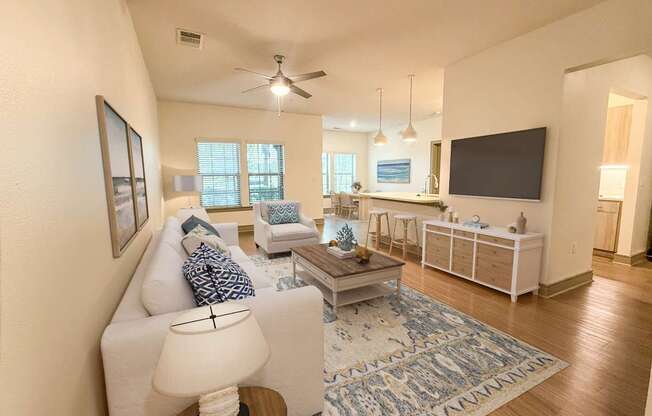 A living room with a white couch, a coffee table, and a flat screen TV.