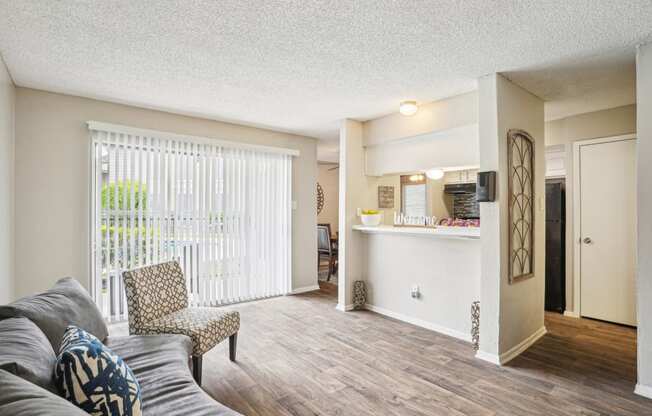 Model A2 floor plan living room with a couch, chair, door to balcony, and view of kitchen Noel on The Parkway in Dallas, TX