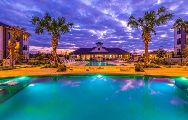 Swimming pool with palm trees and a building in the background at The Parker Austin, Pflugerville, Texas