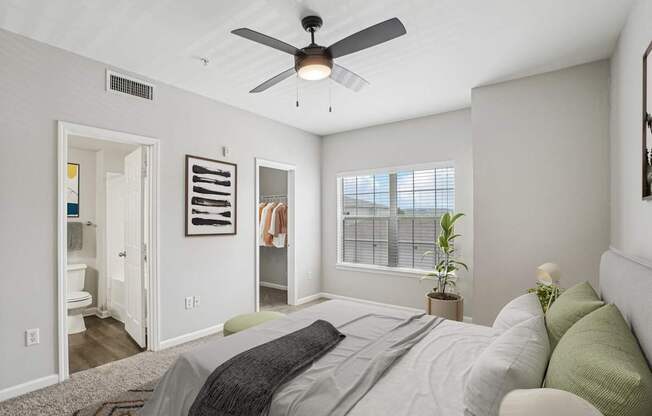 A bedroom with a bed, a ceiling fan, and a window with blinds.