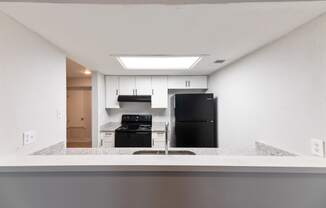 an empty kitchen with a counter top and a black refrigerator