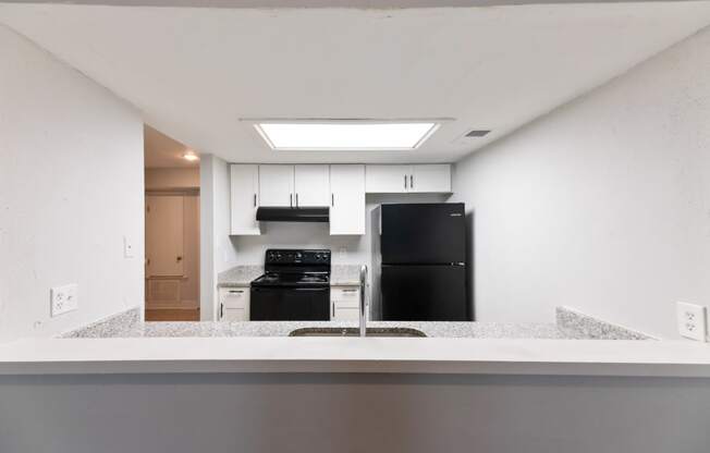 an empty kitchen with a counter top and a black refrigerator