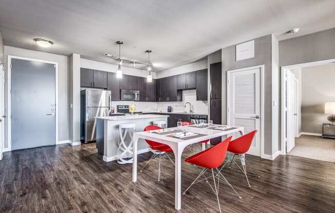 a dining area with a table and chairs and a kitchen in the background