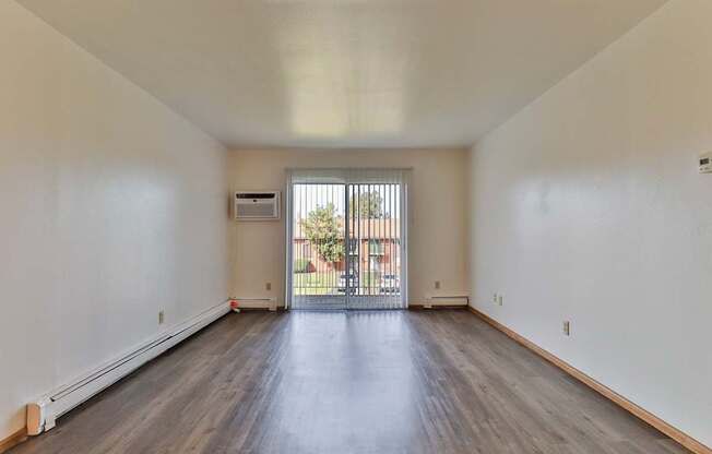 the living room of an apartment with wood flooring and a balcony
