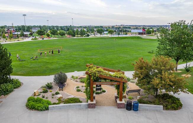 A park with a green field and a wooden archway.