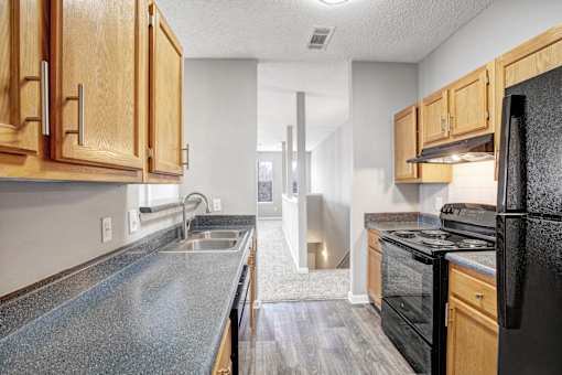 A kitchen with black appliances and wooden cabinets.