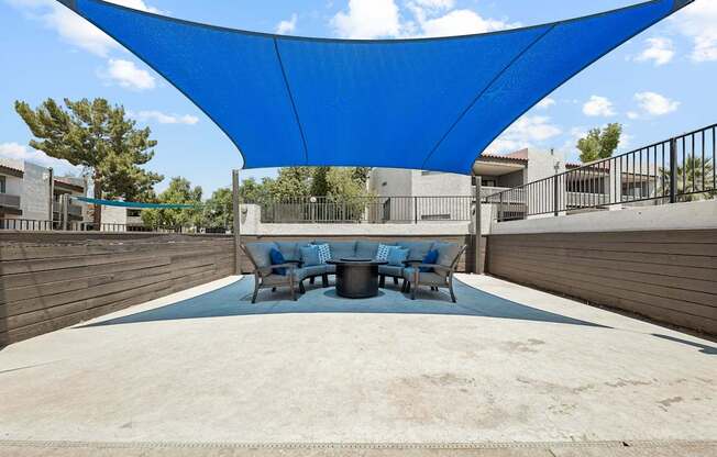 A blue shade structure is over a table and chairs.