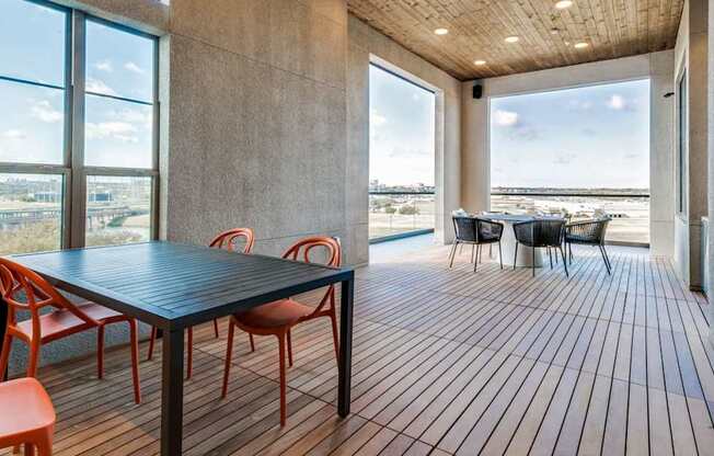 A room with a table and chairs with a view of the beach outside.